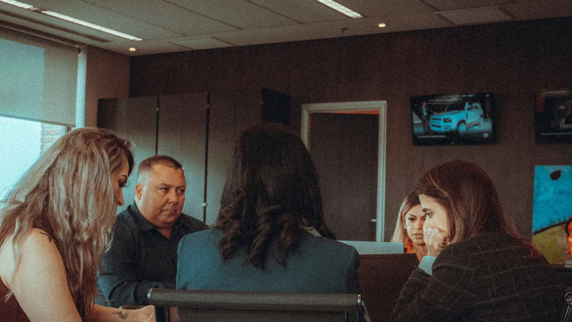 Sala de reuniones con tres cuatro personas hablando sobre temas legales
